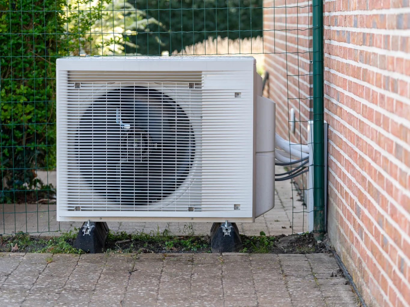 A handyman working on a residential hvac job — mid-task, hands, tools and the work itself in sharp focus, the rest of the space softly out of focus